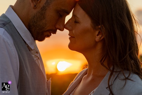 Auch, France — The couple stands head to head in profile in the foreground, with the glowing sunset behind them, creating a dramatic and intimate wedding portrait filled with warm light.