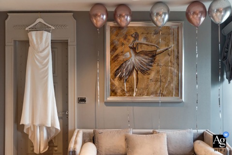 A delicate shot of the bride's white wedding dress, featuring an intricate lace bodice and flowing skirt, is artistically accentuated by a cluster of vibrant balloons inside the Wyndham Grand Kalamis in Istanbul, Turkey.