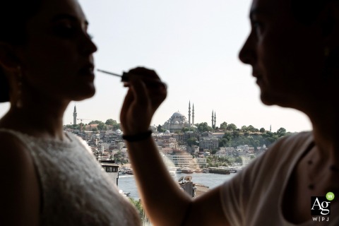 While preparing for her wedding, a bride undergoes her makeup session at The Galata Istanbul Hotel, overlooking a stunning panoramic view of the Turkish old town.