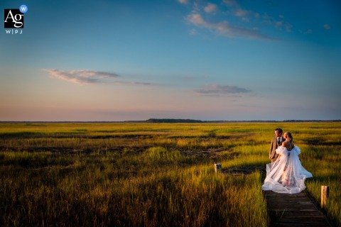 Golden Hour Silhouette: Cape May Wetlands Artistry at Sperlak Gallery Pier's End The Sperlak Gallery in Cape May, NJ, provides the backdrop as the bride and groom stand artfully silhouetted at the end of a pier during golden hour over the serene Cape May wetlands.