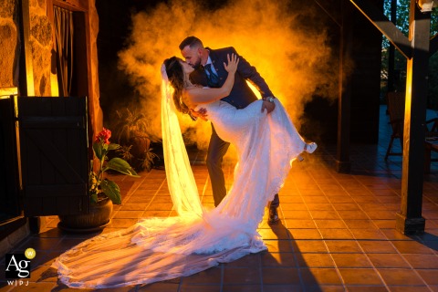 Finca Los Castillos Agroturismo, Mascaraque, Toledo, Spain — At night, the couple shares a dip and kiss in a warmly backlit portrait surrounded by fog or smoke, creating a dramatic and romantic wedding image at the venue.