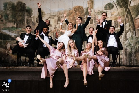 Larmer Tree Gardens, Dorset — The entire bridal party gathers for a stylish group portrait on the stage, sharing a fun and lively session in the picturesque garden venue.