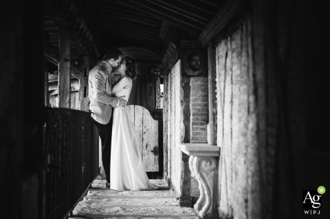 Within the historic stone corridors of Château de Mauriac, the bride and groom share a romantic kiss that highlights the grand scale of the French estate.