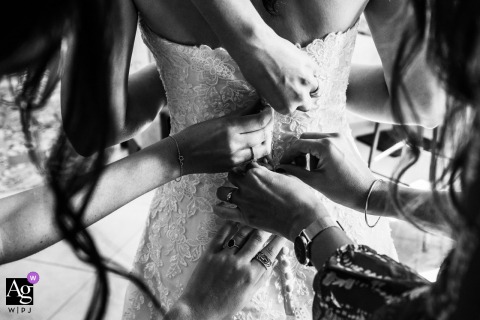 In Toulouse, Haute-Garonne, bridesmaid’s hands carefully adjusts the delicate skirt of the bridal dress at the bride and groom's house, preparing it for the wedding day celebration.