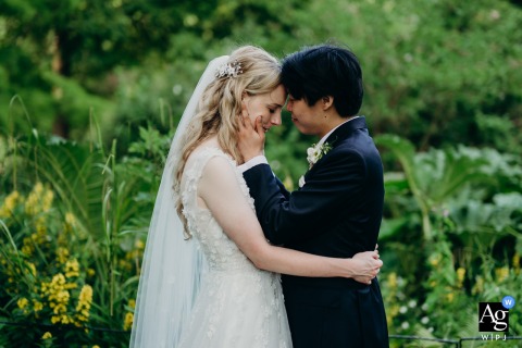 In Botanical Gardens Bath Bride and Groom Stand Face to Face About to Kiss Botanical Gardens, Bath — The bride and groom stand face to face, about to kiss, capturing a quiet scene of connection in a romantic wedding portrait set among the lush gardens.