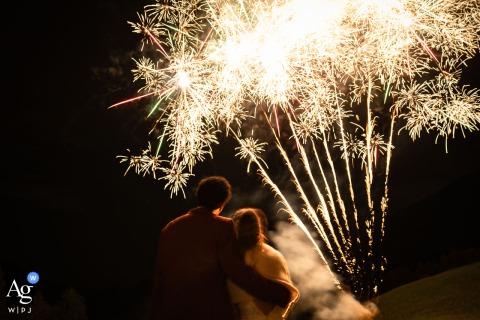 An artistic shot at the Centre Notre Dame de Vette in the Chartreuse mountains, France, shows the newlyweds admiring the bright bursts of color from fireworks lighting up the night sky.