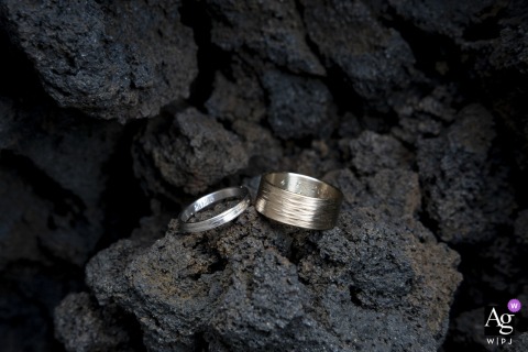 Piscita Beach, Stromboli, Italy: Wedding rings belonging to the couple are photographed artistically on a section of a rough lava wall, standing out against the unique black sand of the volcanic beach.