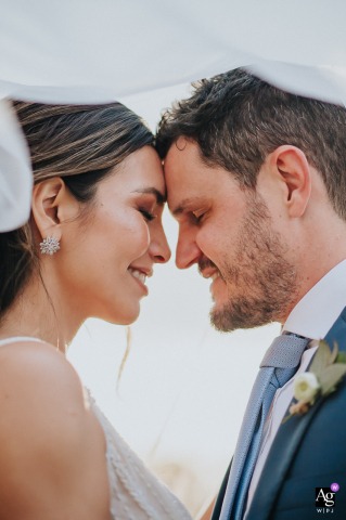 Estancia Santa Lucia, Luján, Buenos Aires — In a tight vertical shot under the bride’s veil, the smiling couple is enveloped together, creating an intimate and romantic wedding portrait at the countryside venue.