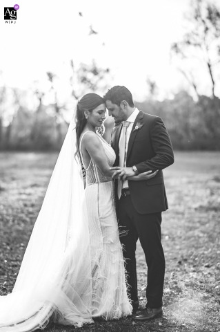 Estancia Santa Lucia, Luján, Buenos Aires — The couple is captured in a dreamy black-and-white vertical portrait outdoors at sunset, embracing in the open countryside for a romantic wedding image.
