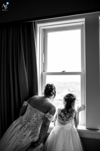 An artistic detail shot captures the bride and her niece in matching dresses observing the ceremony setup through a window in Edmonton, Alberta.
