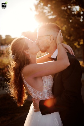 Warm Sun Rays Envelop The Couple Outside Their Wedding Reception Venue In The Fribourg Region Switzerland Warm sun rays envelop the bride and groom as they share a long kiss outside their wedding reception venue in the beautiful Fribourg region of Switzerland.