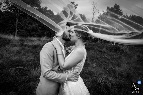 The vast open landscape of Rucphense heide, Rucphen offers a creative environment for this wedding day portrait, beautifully illustrating the movement of the bride's veil as it drifts above them.