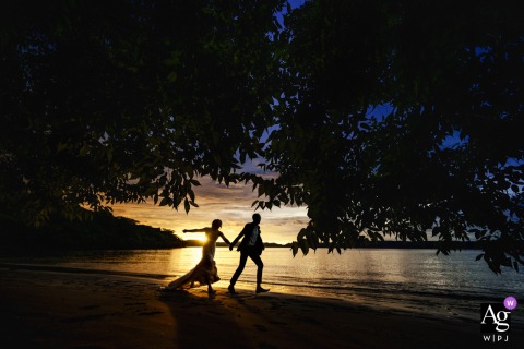 Secrets Papagayo Costa Rica, Liberia - Guanacaste, provides the artistic setting for this wedding portrait, capturing the silhouette of the bride and groom running together across the beach during their portrait session.