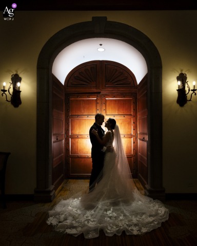 Costa Rica Marriott Hacienda Belén Hotel — The bride and groom appear in silhouette, creatively framed by the hotel's architecture in profile, with a spotlight on the door behind them adding dramatic contrast to this artistic wedding portrait.