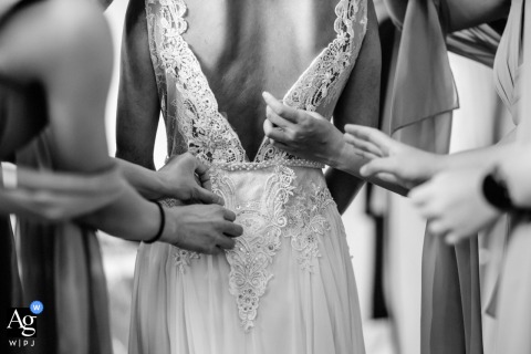 The intricate wedding day details in San Francisco, California, are shown through an artistic photograph of multiple people's hands gently arranging the bride's dress at the ceremony location.