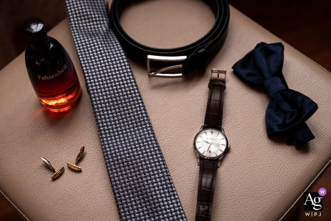 San Michele Al Tagliamento, Udine, Italy, is the setting for this artistic composition showcasing the groom's wedding day details, including his sophisticated watch, bow tie, and belt laid out together thoughtfully.