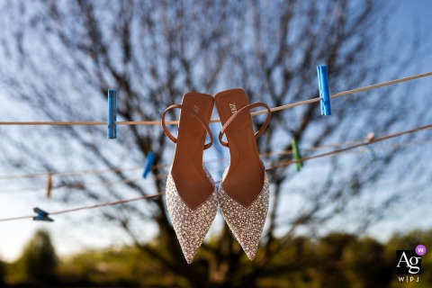 San Michele Al Tagliamento, Udine, Italy, features a charming artistic detail of the bride's wedding shoes dangling by the laces from a rustic clothesline on the big day.