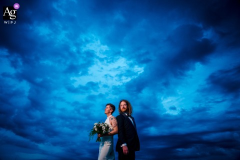 Old Town Alexandria Blue Hour: Couple's Minimalist Portrait Against The Twilight Sky Old Town, Alexandria — During blue hour at the reception venue, the couple stand back to back and look in the same direction, framed low and center in a minimalist wedding portrait against the twilight sky.
