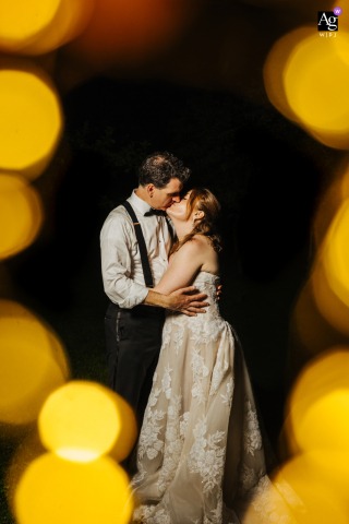 Liberty View Farm, New York — Surrounded by fairy lights at night, the couple stands in a vertical portrait with glowing orange bokeh framing the edges, giving the wedding image an artistic atmosphere.