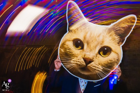 Wedding Guest On The Dance Floor Holds A Cardboard Cat Cutout Surrounded By Swirling Artistic Light Trails And Energy Wedding guest on the dance floor holding a cardboard cat cutout, surrounded by artistic light trails.