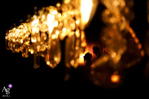   Through the sparkle of a chandelier at a Dordogne reception venue in Nouvelle-Aquitaine, the couple is artfully photographed, the light creating a unique and stylish wedding portrait.