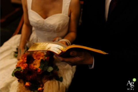 Couple Looks Through Golden Lit Bible at Beijing Xishiku Church in a Shared Wedding Detail At Beijing Xishiku Church, a couple looks through a golden-lit Bible together, captured in a detail of shared focus during their wedding day.