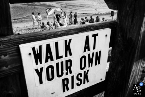   On Provincetown Beach in Massachusetts, the ceremony is cleverly framed through a beach warning sign, blending humor and artistry as the couple begins their new journey.