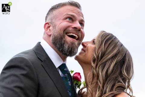 Bride and Groom Laugh on Shores of Lake Oconee in Eatonton Georgia During Portrait On the shores of Lake Oconee in Eatonton, Georgia, the bride and groom laugh together during a posed outdoor portrait session, reflecting a relaxed atmosphere.