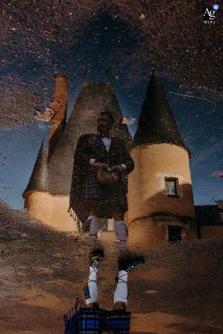At Chateau des Stuarts In Cher, The Groom’s Reflection Appears In A Puddle, Adding Drama To The Historic Venue Scene At Chateau des Stuarts in Cher, the groom’s reflection appears in a puddle, the dramatic composition adding intrigue to the castle’s historic setting.