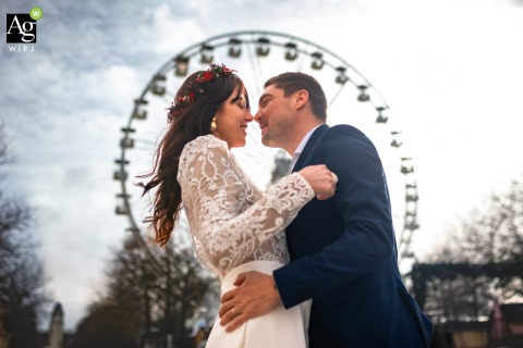 Couple Poses Near Large Ferris Wheel in La Rochelle Charente Maritime France for Session The couple is pictured near a large Ferris wheel in La Rochelle, Charente Maritime, France, using a local landmark to anchor their session in the city’s fun landscape.
