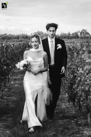 Newlyweds Walk Through Château Larteau Vineyards in Gironde France Together The newlyweds walk through the lush vineyards of Château Larteau in Gironde, France, during their romantic couple session.
