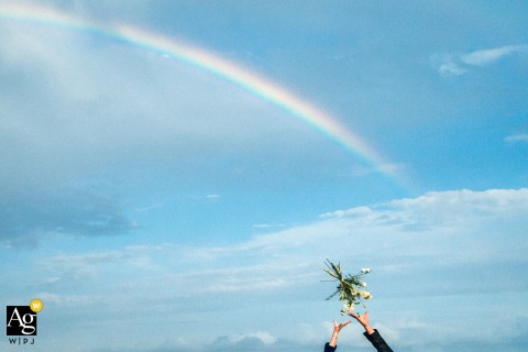 At Fort La Prée, Ile de Ré, Guests Eagerly Watch The Bride’s Rainbow Bouquet Toss Fly Through The Air Also at Fort la Prée, Ile de Ré, the scene features a colorful bouquet toss, with guests eagerly watching the bride’s rainbow-themed flowers flying through the air.