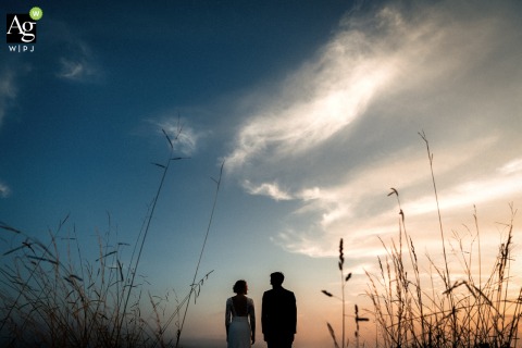 Silhouetted Couple at Domaine Etxezahar in Bardos France Stands Against Dramatic Dusk Sky Landscape A couple is featured in a silhouette portrait at Domaine Etxezahar in Bardos, France, presenting formal attire against the venue’s natural landscape and the dusk sky.