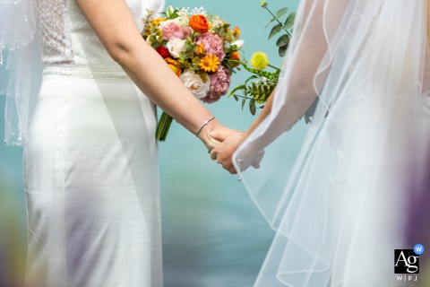 Detail Of The Couple Holding Hands With Bouquet Flowers At Lake Tekapo In New Zealand Lake Tekapo wedding detail image of couple holding hands with bouquet flowers being held.