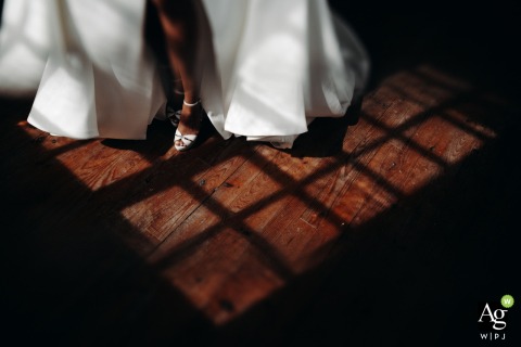 Light and Shadow Accentuate Bride’s Shoe Details by Window at Chateau in Gers France Light and shadows from a grid window falls on the bride’s shoe at Chateau - Gers, emphasizing the texture and design as part of the wedding attire details.