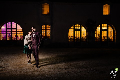 Illuminated Architecture and Nighttime Backdrop Set the Mood for Couple Portrait at Abbaye du Val des Choues At the Abbaye du Val des Choues, a couple is photographed at night in front of the illuminated venue, the portrait relying on low light and architectural background for atmosphere.