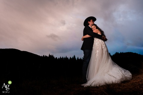 Sunset Light and Landscape Frame Couple’s Embrace at Grizzley Gardens in Montana At Grizzley Gardens in Montana, a couple embraces as the sun sets, using the natural light and landscape to frame the end-of-day portrait.