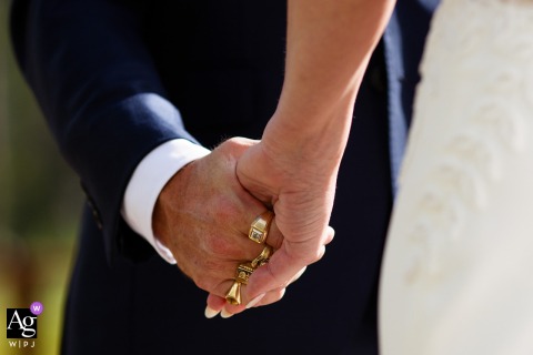 Close-Up At Piney River Ranch In Colorado Focuses On The Groom’s Rings As He Holds The Bride’s Hands During Ceremony During the ceremony at Piney River Ranch, Colorado, a close-up captures the groom’s rings as he holds hands with the bride, focusing on the meaningful detail of their union.