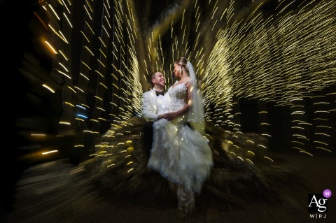 Dramatic Night Portrait With The Bride And Groom Illuminated By Tree Lights In Front Of Hacienda Sitio De Mata Gardens A dramatic night portrait captures the bride and groom illuminated by tree lights in front of Hacienda Sitio de Mata, their figures glowing in the reception venue’s gardens.