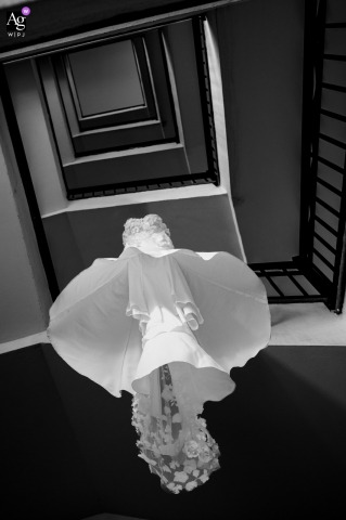 The Bride’s Dress Cascades Like A Blooming Flower Along The Staircase In Los Cabos, Elegantly Displayed For Dramatic Effect Along the staircase in Los Cabos, the bride’s dress hangs and cascades down, its fabric elegantly displayed and shaped like a blooming flower.
