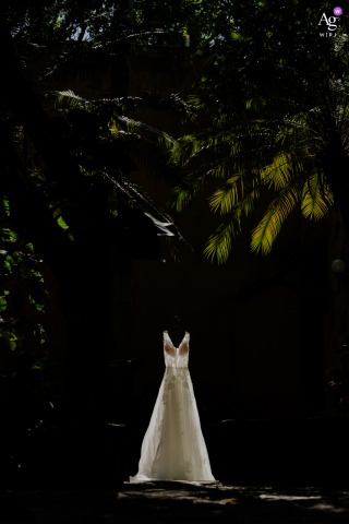 The Bride’s Dress Is Displayed Against Sun-Drenched Colonial Hacienda Walls In Mérida, Yucatán, Mexico, Light Enhancing Its Texture In Mérida, Yucatán, Mexico, the bride’s dress is displayed against a backdrop of sun-drenched colonial hacienda walls, the natural light enhancing the dress’s elegant texture.