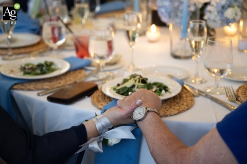 Mother of Bride Clasps Friend’s Hand Listening to Emotional Toast at Popponesset Inn Massachusetts At Popponesset Inn in Mashpee, Massachusetts, the mother of the bride clasps a friend’s hand, emotion evident as she listens to her husband’s heartfelt wedding toast.