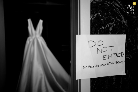 In An Edmonton Hotel, The Bride’s Dress Hangs In The Closet With A Sign, Creating A Unique Bridal Detail In an Edmonton hotel, the bride’s dress hangs neatly in the closet, accompanied by a sign and a warning, creating a behind-the-scenes bridal detail.