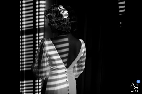 Window Light Casts Distinct Patterns Across The Bride As She Prepares At Home In Edmonton, Alberta At home in Edmonton, Alberta, the bride prepares for her wedding, bathed in window light that casts distinct patterns across the room.