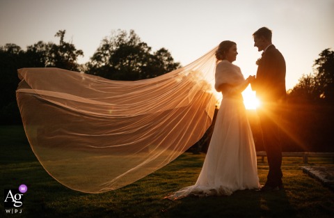 The Bride’s Veil Is Illuminated By Golden Sunset Light At Hale Park In Hampshire, Highlighting A Dreamy Elegant Wedding Detail Sunset at Hale Park in Hampshire, UK, highlights the bride’s veil, its fabric illuminated by the golden light for a dreamy and elegant wedding detail.
