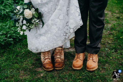 Wearing Timberlands, The Bride And Groom Walk Through Mud On Kelston Roundhill In Bath, Adding Fun To Classic Attire Wearing Timberlands, the bride and groom walk together through the mud on Kelston Roundhill in Bath, their rugged footwear a fun twist on classic wedding attire.