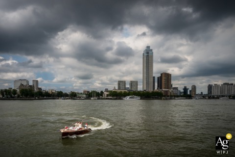 Navigating By Boat Along The Maas In Rotterdam, The Couple Heads Toward Wereeldmuseum, Capturing A Modern Wedding Journey Along the Maas in Rotterdam, the wedding couple navigate by boat toward the Wereeldmuseum, capturing a modern journey through the city’s iconic waterways.