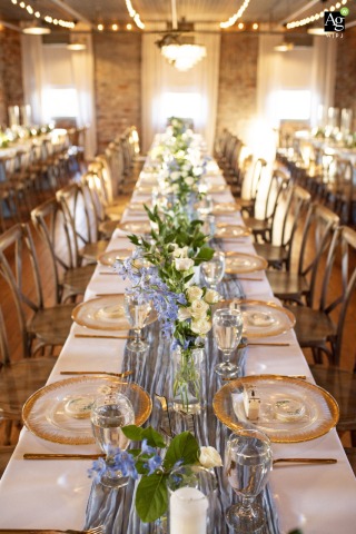 Long, Elegant Reception Table Arrangements Reflect Unique Wedding Style at Savannah Bottleworks in Georgia A beautifully arranged reception table is set at Savannah Bottleworks in Savannah, Georgia, with flowers and elegant place settings reflecting the couple’s unique wedding style.