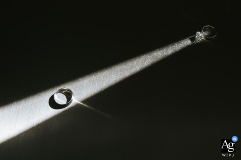 A Sunbeam Illuminates A Wedding Ring At An Ohio Getting Ready Location, Turning A Classic Detail Into An Artistic Composition At a getting ready location in Ohio, a wedding ring is photographed illuminated by a sunbeam, turning a classic detail into a striking and original composition.