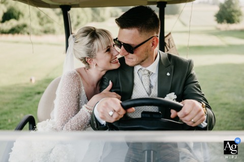 The bride and groom share a playful and relaxed portrait in a golf cart at Golf Payerne, Switzerland, surrounded by greenery At Golf Payerne in Switzerland, the bride and groom sit together in a golf cart, capturing a playful and relaxed portrait amid the course’s greenery.